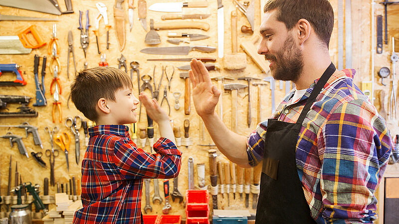 Carpenter father and son making high five at workshop